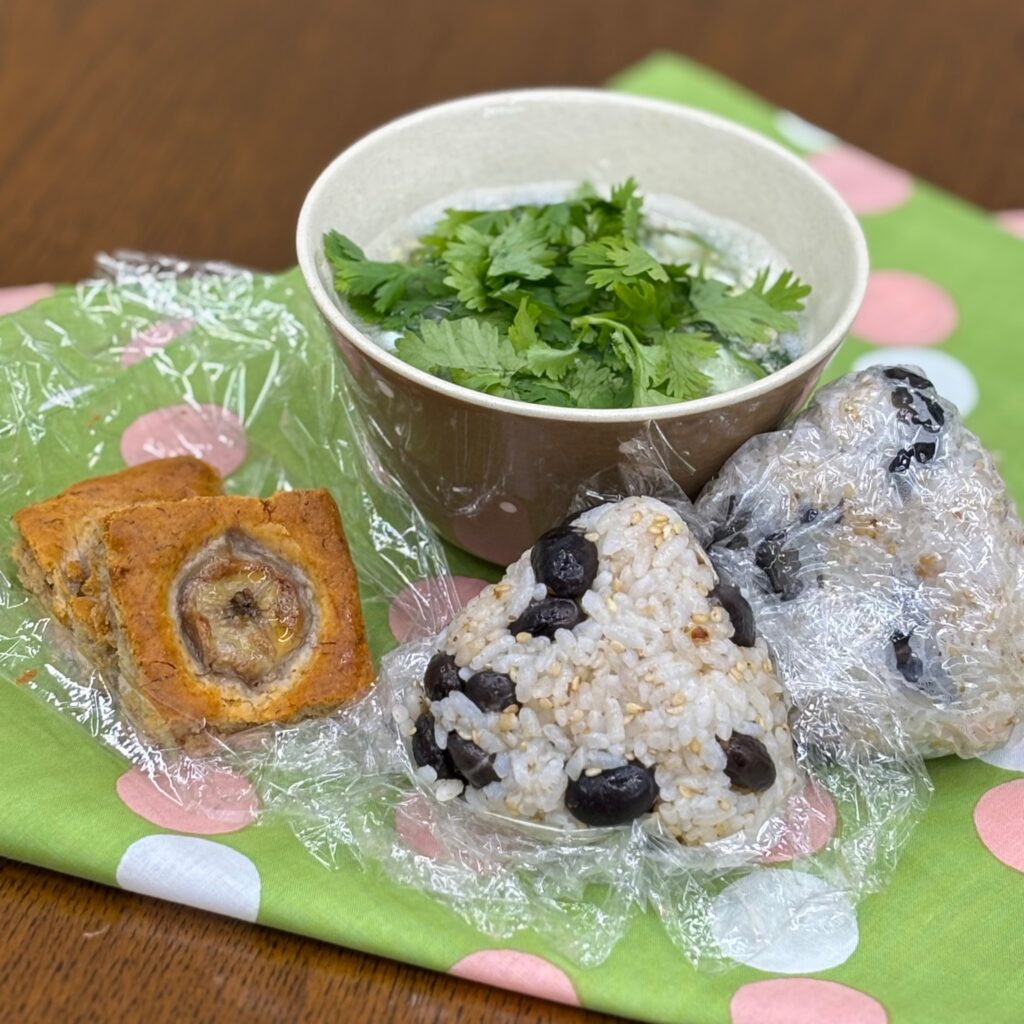 A lunch set with black bean rice balls and a soup topped with cilantro. For dessert, banana cake.