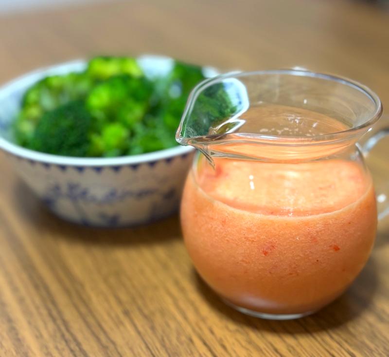Homemade onion dressing in a glass container with a bowl of broccoli