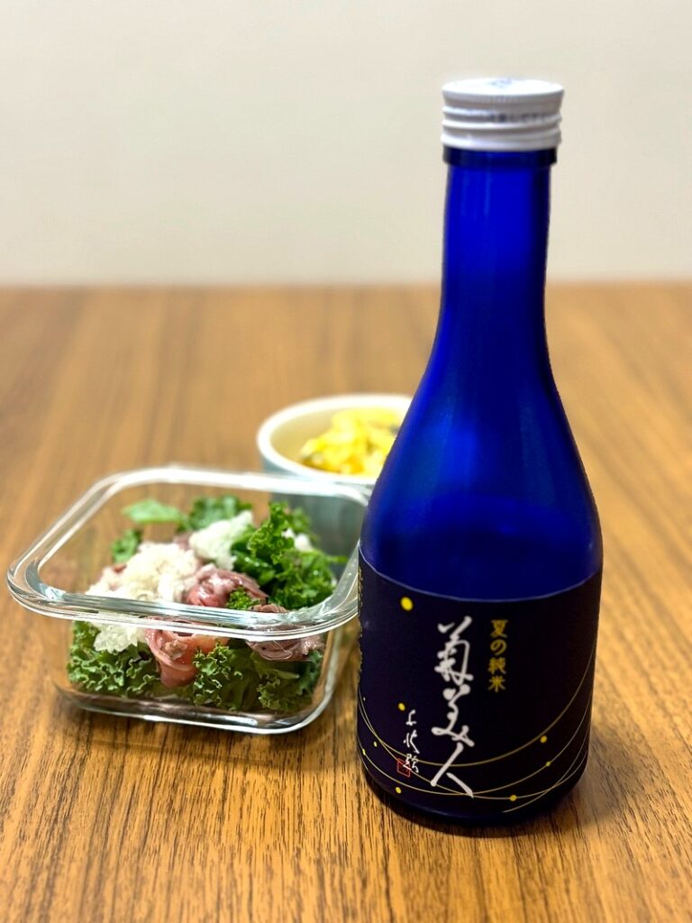 “Kikubijin Summer Junmai” sake in a dark blue bottle, served with roast beef marinade and pumpkin salad.
