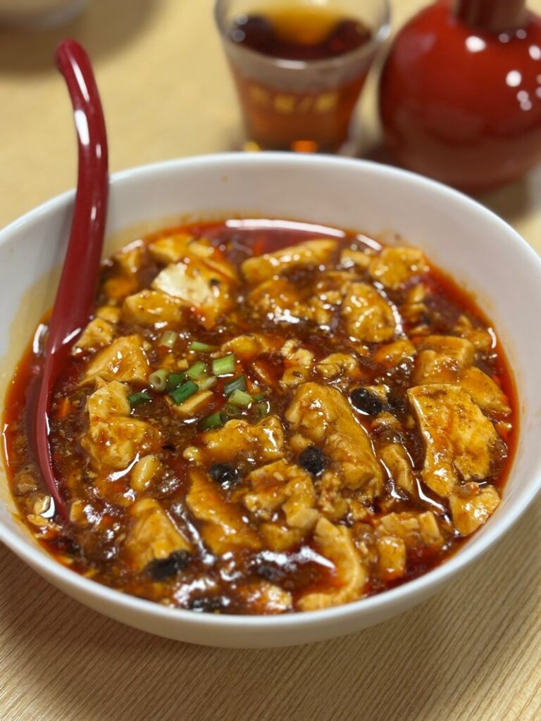 Authentic Sichuan-style mapo tofu with doubanjiang and whole Sichuan peppercorns in a rich red sauce