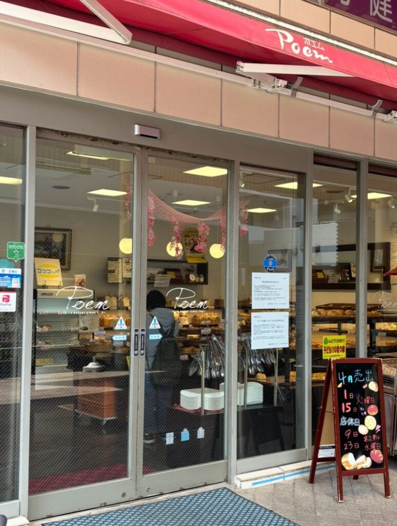 Exterior of “Poem Main Store” in Tojinmachi Shopping Street. A glass-front bakery with freshly baked bread inside.