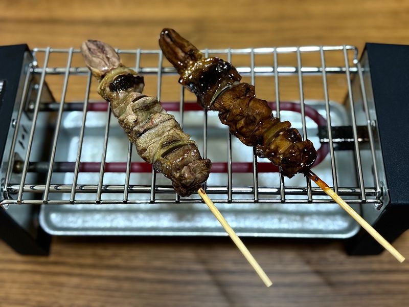 Chicken liver skewers (salted and sauced) being reheated on a tabletop grill called “Senbero Maker”