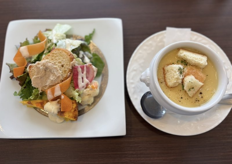 A vibrant salad with various fresh ingredients and a creamy potage soup topped with croutons. The colorful presentation is truly appetizing.