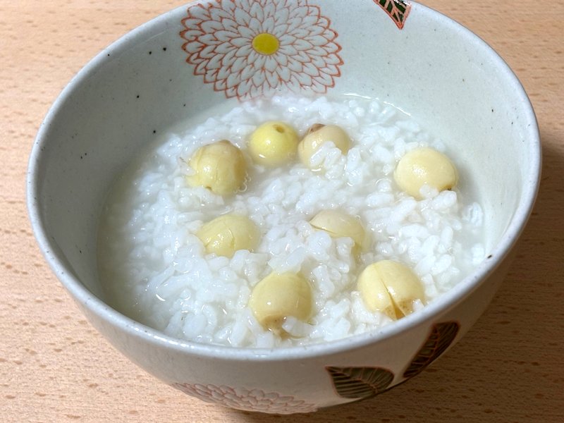 Finished dish of rice porridge with lotus seeds, gently colored and comforting in appearance.