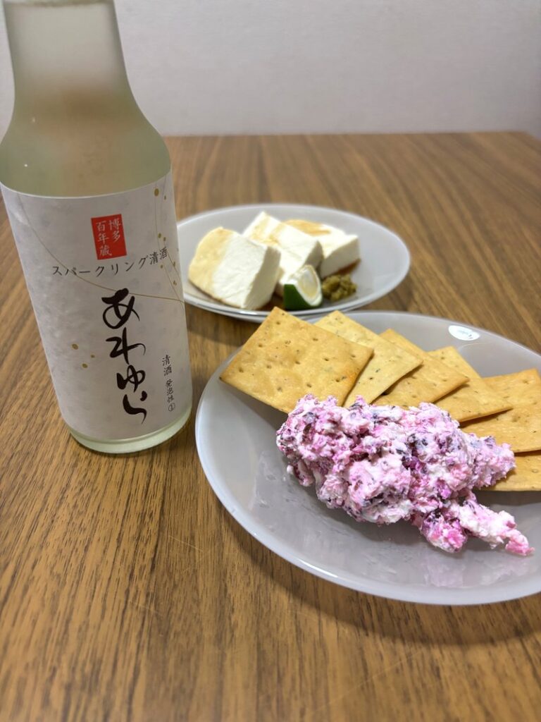 Sparkling sake “Awayura” paired with crackers topped with shibazuke cream cheese, and silken tofu with yuzu kosho in the background.
