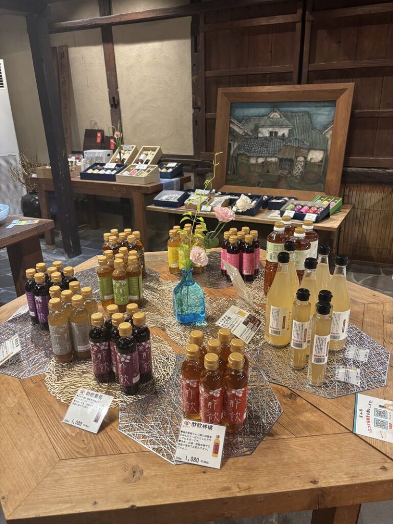 Interior sales area of Shobunzu, featuring colorful vinegar drink bottles arranged on a wooden table.