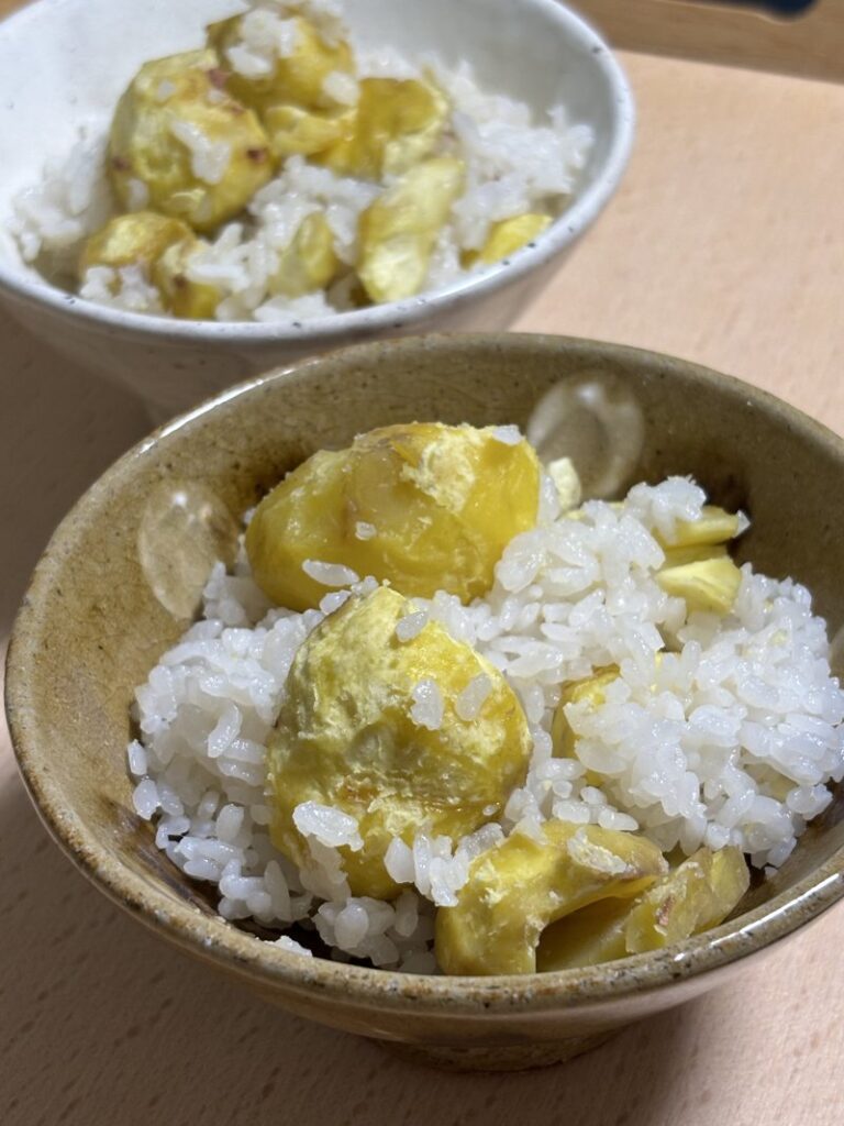 Bowl of rice with large chestnuts mixed in, served in a rustic dish.