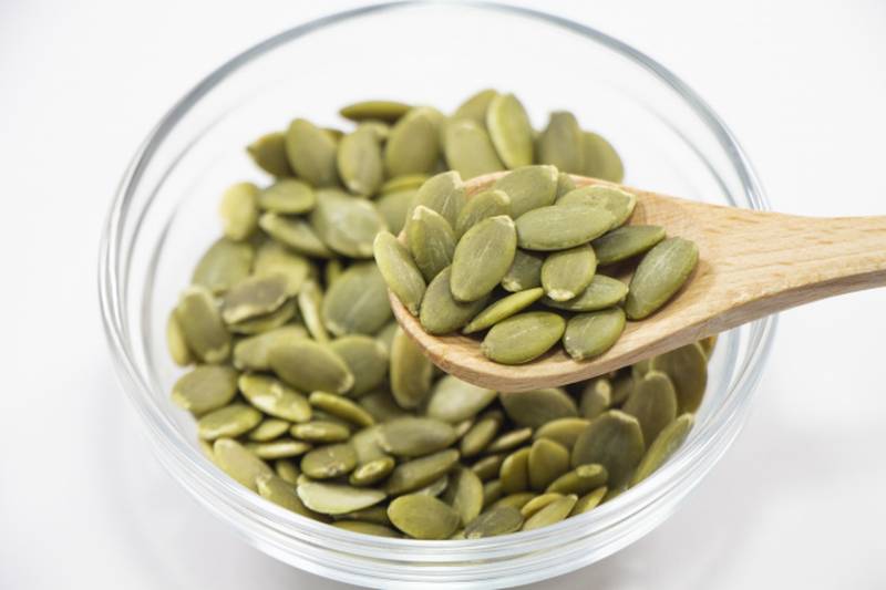 A photo of pumpkin seeds in a glass bowl.