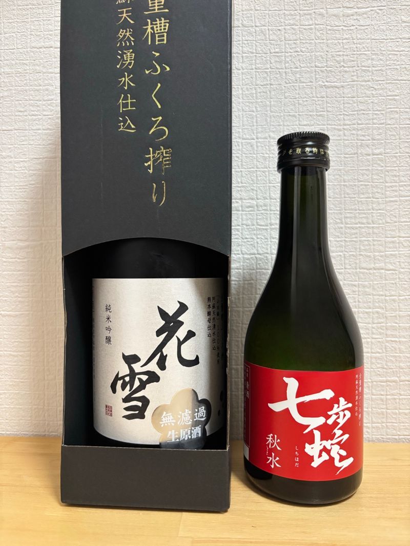 Bottles of Kawazu Brewery’s “Hanayuki” Junmai Ginjo and “Shichihoda Shūsui” Tokubetsu Junmai, with the black boxed Hanayuki and red-labeled Shichihoda side by side.