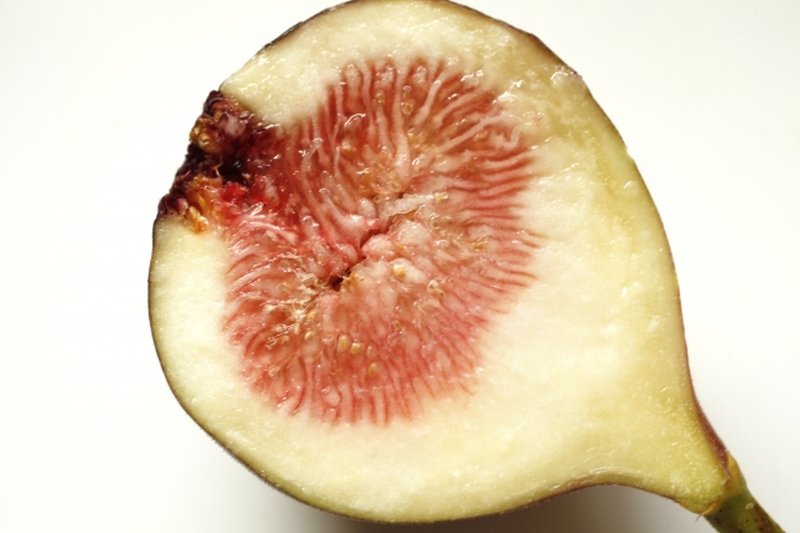 Cross-section of a fig showing the white grain-like flowers inside the red flesh.