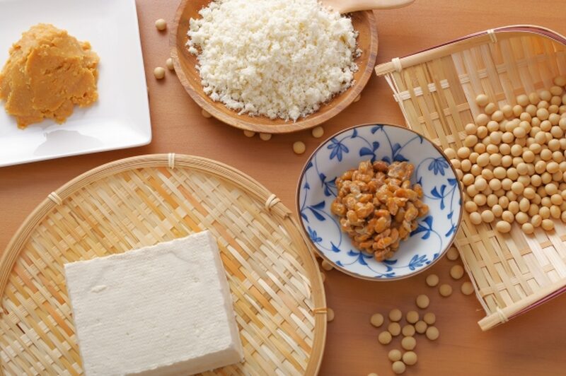 Various Japanese soybean foods including tofu, natto, miso, okara, and whole soybeans.