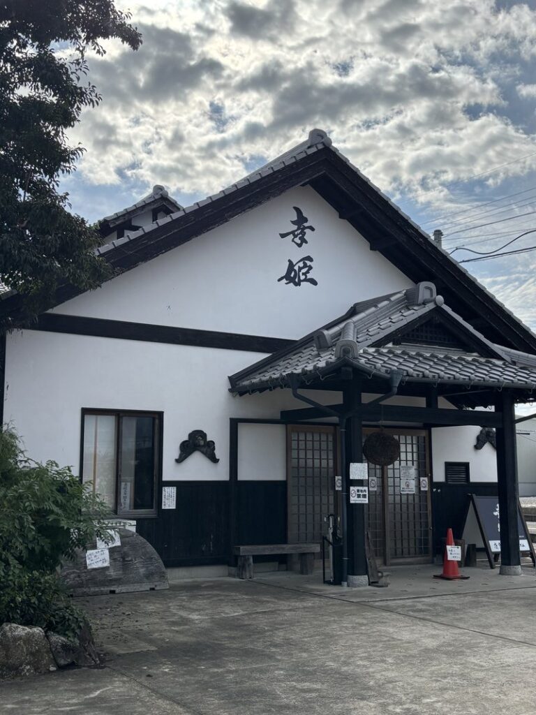 Exterior of Sachihime Sake Brewery, featuring white plaster walls and a tiled roof with the name “Sachihime” written on the façade.