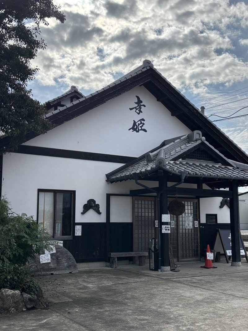 Exterior of Sachihime Sake Brewery, featuring white plaster walls and a tiled roof with the name “Sachihime” written on the façade.