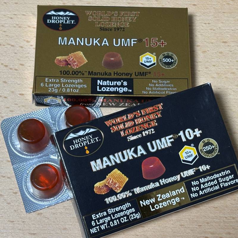 Packages of HONEY DROPLET solid Manuka honey lozenges, UMF10+ and UMF15+, with amber-colored drops in blister packs.
