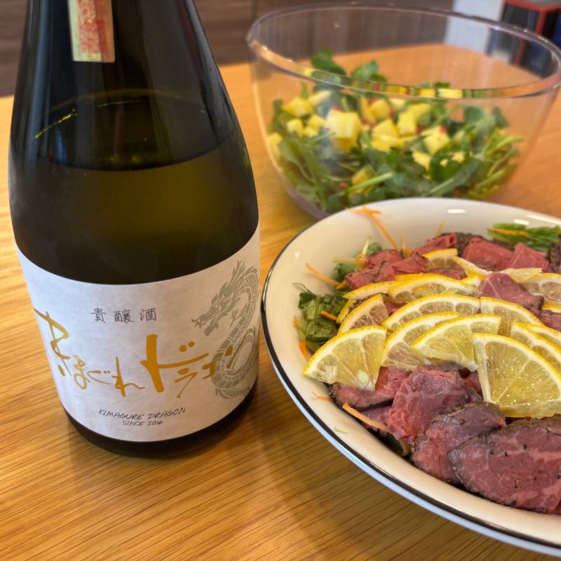 A photo of “Kimagure Dragon” sake from Mitsutake Brewery served with a roast beef salad on a Christmas table