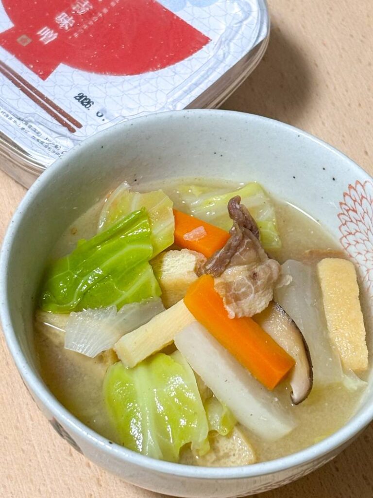 A hearty bowl of miso soup filled with cabbage, carrot, daikon, mushrooms, pork, and fried tofu.