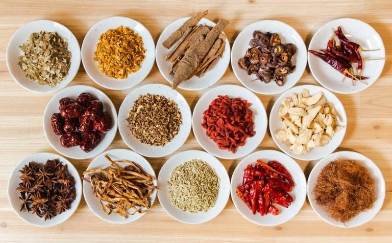 Dried medicinal herbs and spices used in Chinese herbal medicine and dietary therapy, arranged on small plates