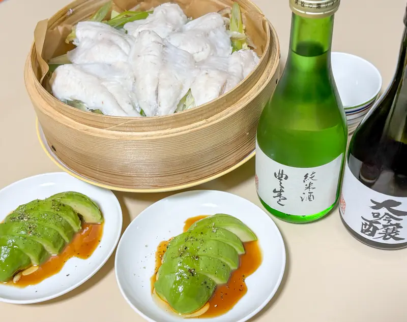 Bottles of "Toyosakari" sake — daiginjo and junmai varieties from Toyomura Brewery — alongside a steamed dish of lenko-dai (yellowback sea bream) prepared at home.