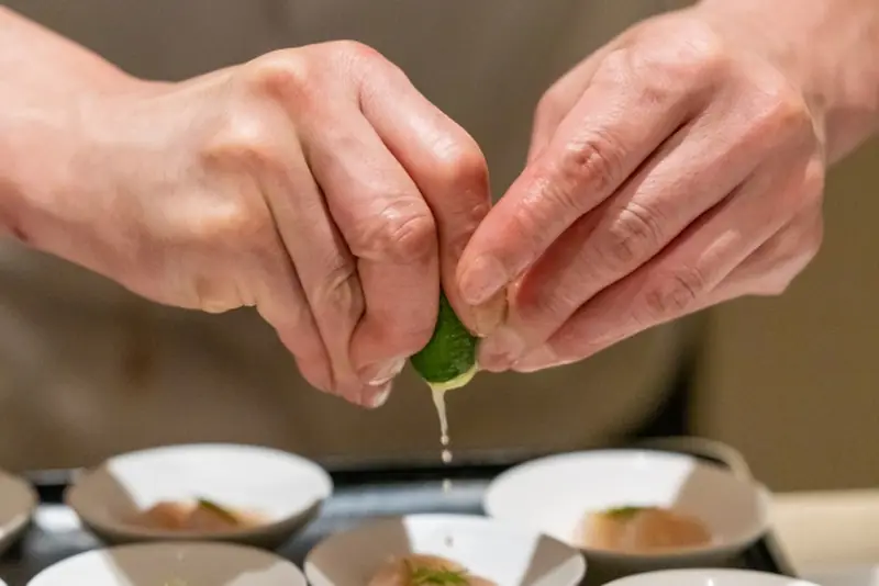 Hands squeezing green sour citrus over a dish